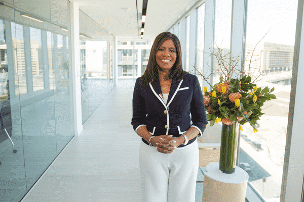 Dr. Harris poses outside of builing in white pants and blue blazer