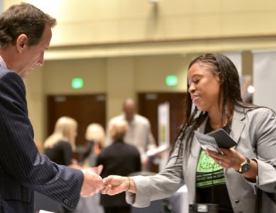supplier diversity executive accepting business card from an attendee at the matchmaker session