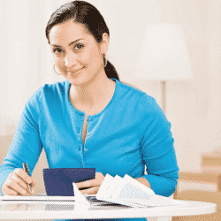 latina woman sitting at desk with checkbook and paperwork