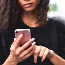 Closeup image of a woman holding, using and looking at smart phone with feeling happy