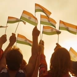 A group of people, mostly women, holding small Indian flags in the air.