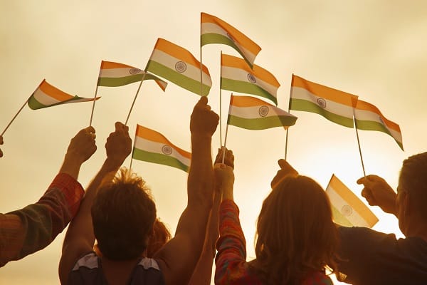 A group of people, mostly women, holding small Indian flags in the air.