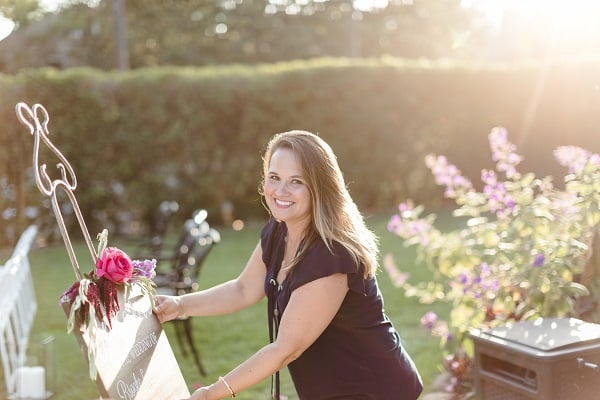 Amy Grace decorating for an outdoor wedding while looking at the camera