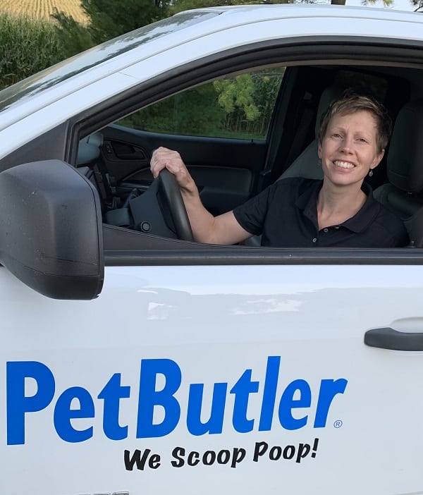 Kelly Amundson sitting behind the wheel of her Pet Butler work vehicle that says We Scoop Poop