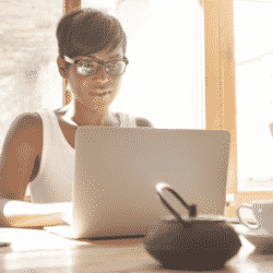 woman working on her computer at table with filtered light coming through window