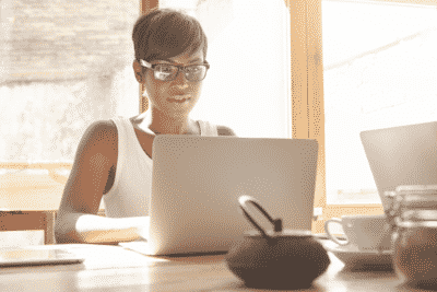 woman working on her computer at table with filtered light coming through window