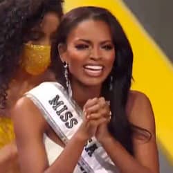 Miss USA pageant winner Asya Branch smilign with sash on and clasping hands