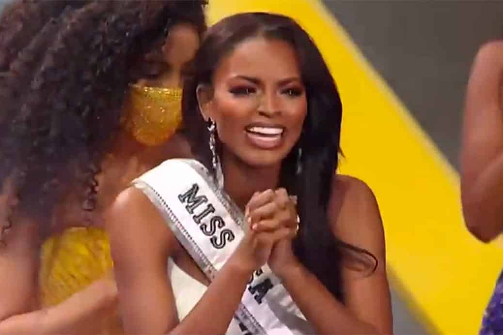 Miss USA pageant winner Asya Branch smilign with sash on and clasping hands