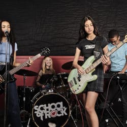 group of diverse music students in school playing guitars and drums