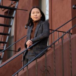 Asian woman standing on stairs wearing a grey suit