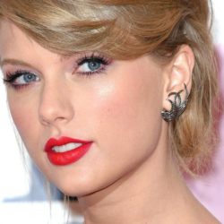 Taylor Swift pictured wearing red lips while looking at the camera with her hair up