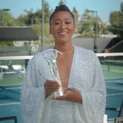 Naomi Osaka pictured in a white gown while holding her sports trophy