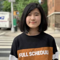 Emma Yang outdoors wearing a black and gold long sleeved sweater that says full schedule