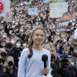 Greta Thunberg standing in front of a crowd protesting climate change