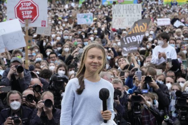 Greta Thunberg standing in front of a crowd protesting climate change
