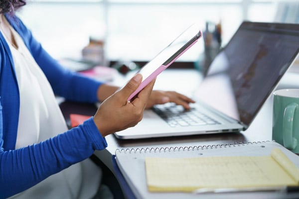 Latina woman working from home with laptop and smartphone in her hand