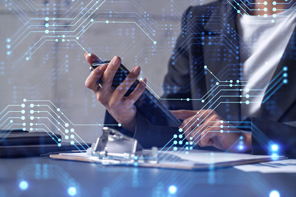 Businesswoman at desk checking phone with tech graphs in background