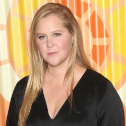 Amy Schumer wearing a black top while smiling at the camera