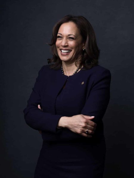 Vice president Kamala harris smiling away from the camera while wearing a pantsuit.