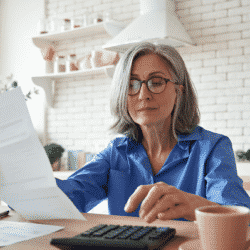woman seated at kitchen table reviewing financial documents
