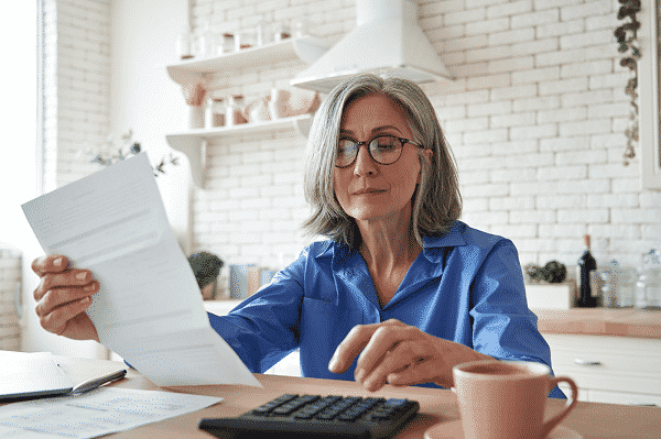 woman seated at kitchen table reviewing financial documents