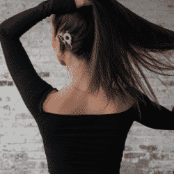 Abigail Heringer with her back facing the camera as she lifts her hair to show her new cochlear implant