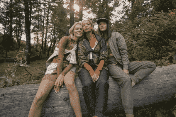 Three women sitting on a tree stump in the outdoors