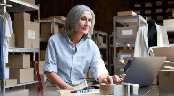 female business owner looking at a laptop in her warehouse