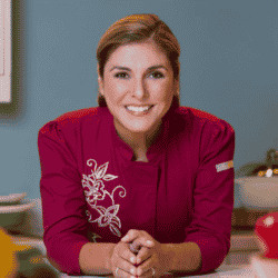 Renowned Latina chef Lorena Garcia wearing a red chefs uniform while smiling at the camera