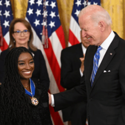 Joe Biden putting the Presidential Medal of Freedom award on Simone Biles