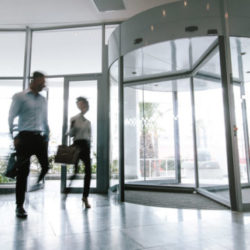 Motion blurred shot of two business people talking through modern office hallway. People walking in office entrance hall.