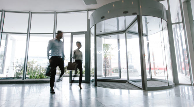 Motion blurred shot of two business people talking through modern office hallway. People walking in office entrance hall.