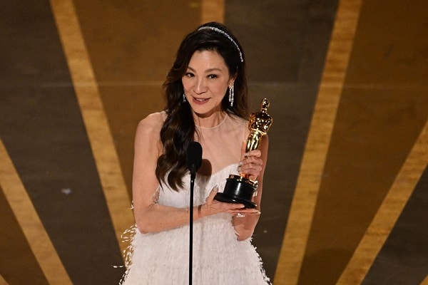 michelle yeoh with oscar in hand smiling on stage